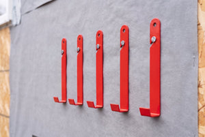 Five EZpanl hooks nailed in a level line to housewrap, each hanging on one 8d sinker driven through its angled slot, forming a support line ready for a panel